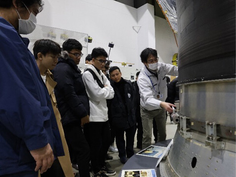 JAXAにてロケットや探査機,人工衛星に関する説明を聞くIUHからの参加者